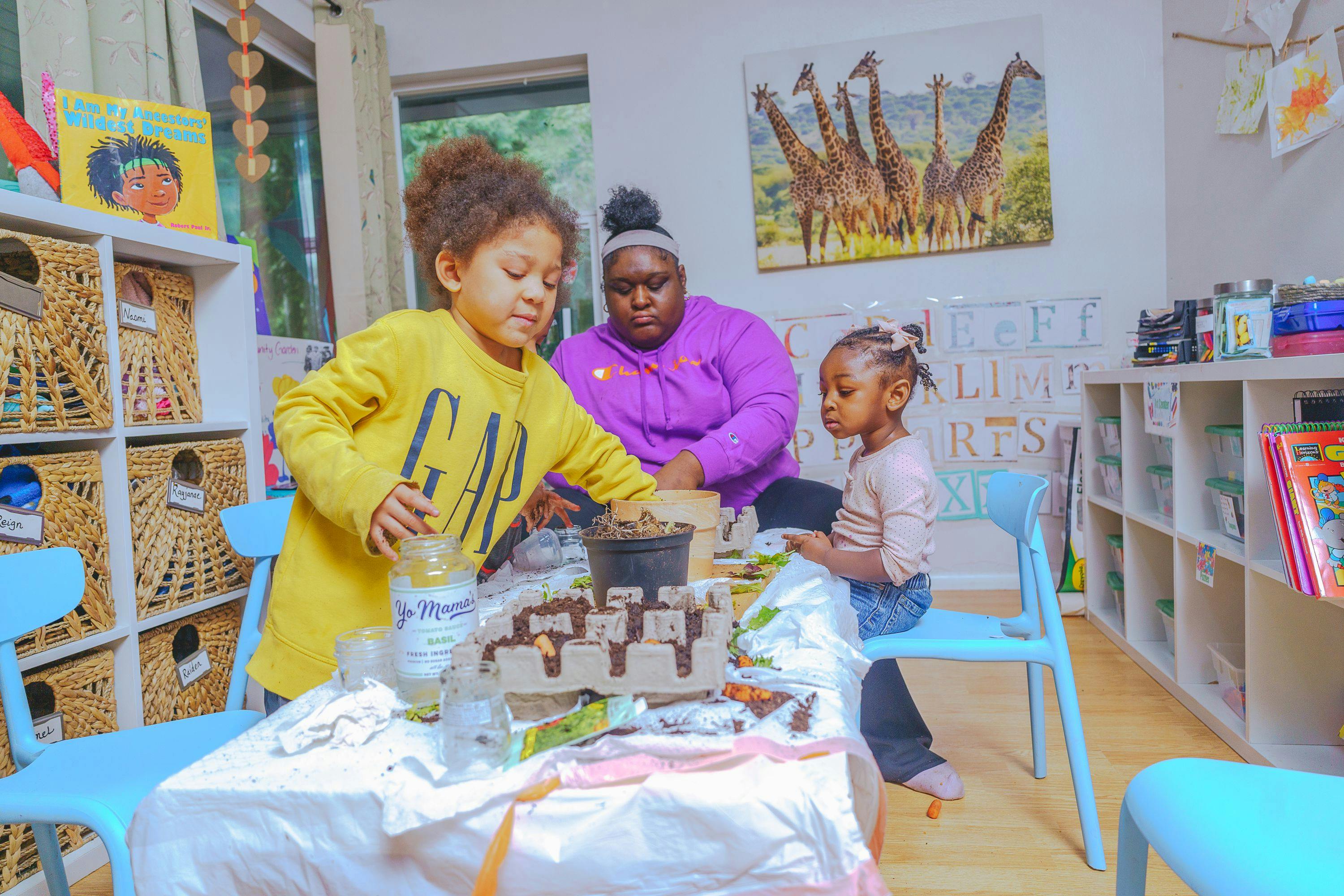 Adult and two children planting seeds at a table in a classroom