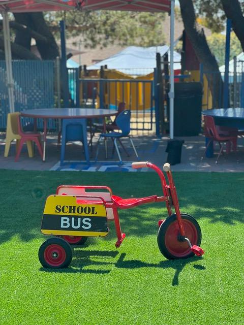 Red tricycle with a yellow and black "SCHOOL BUS" sign on the back