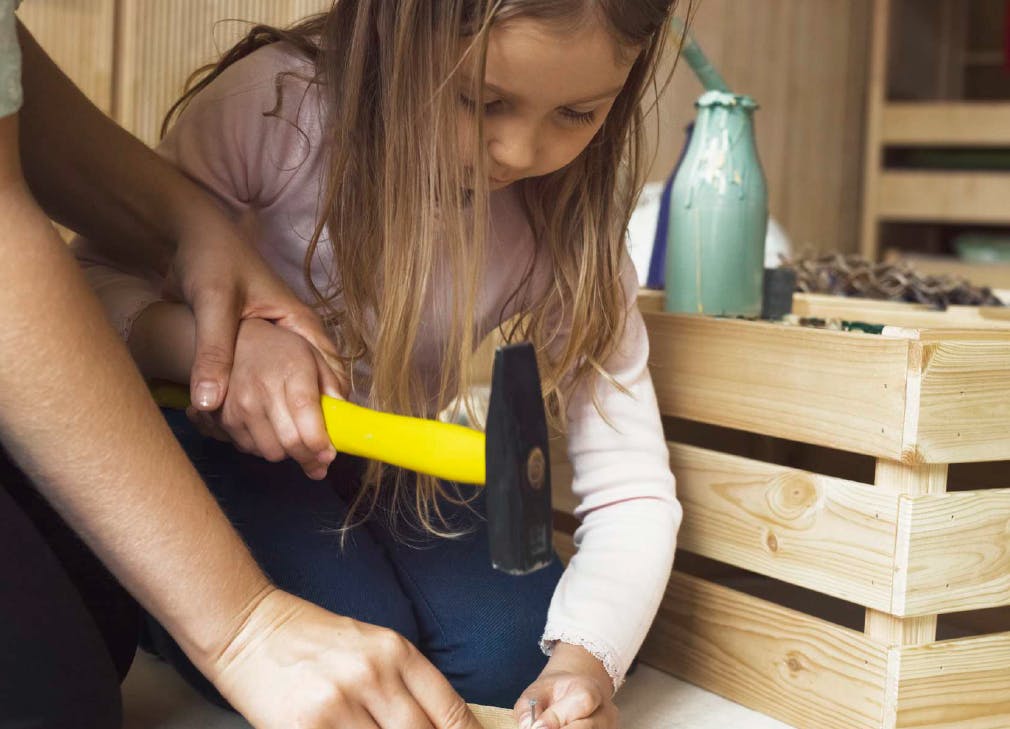 Adult helping child hold a hammer