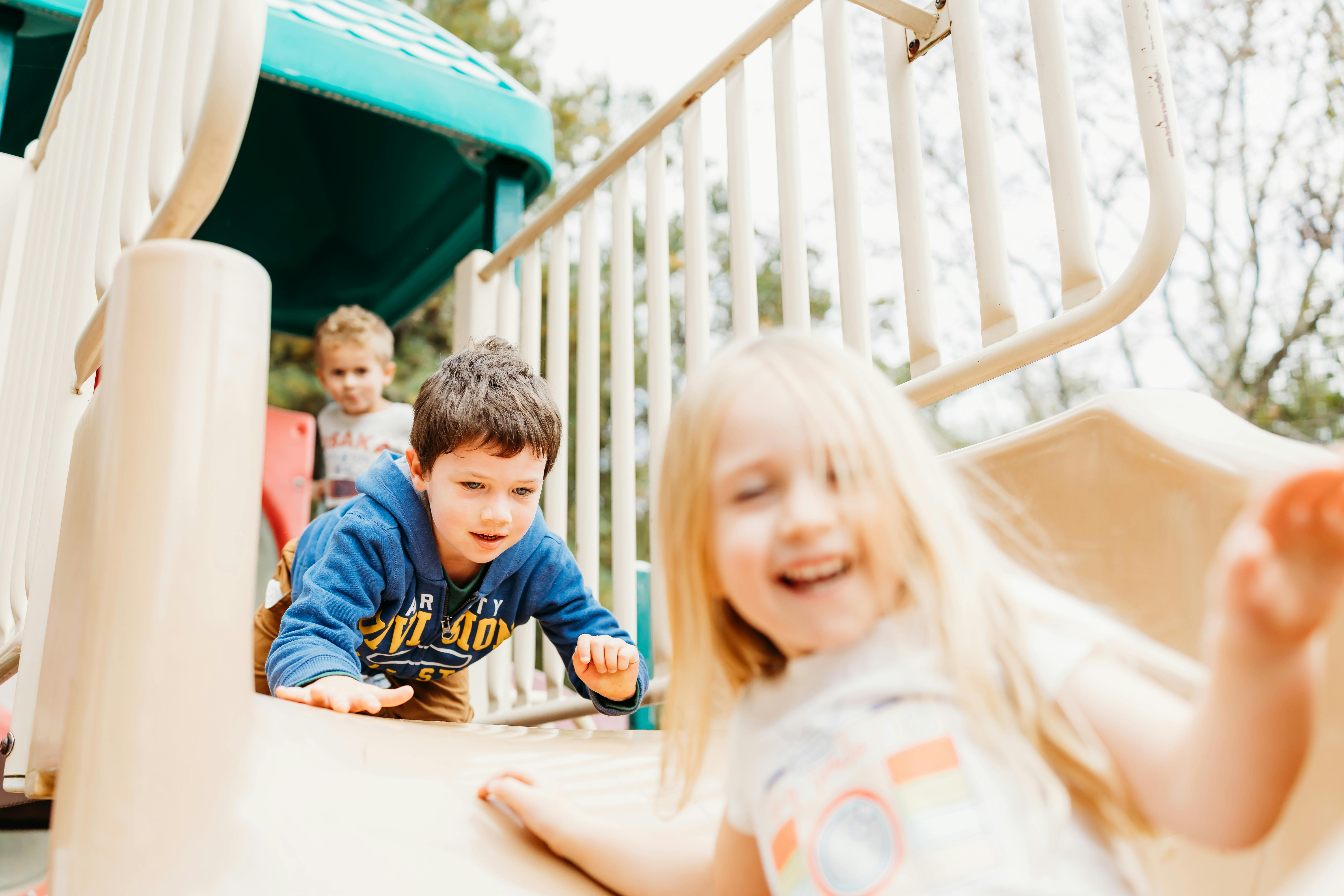 Three children playing on a playground slide