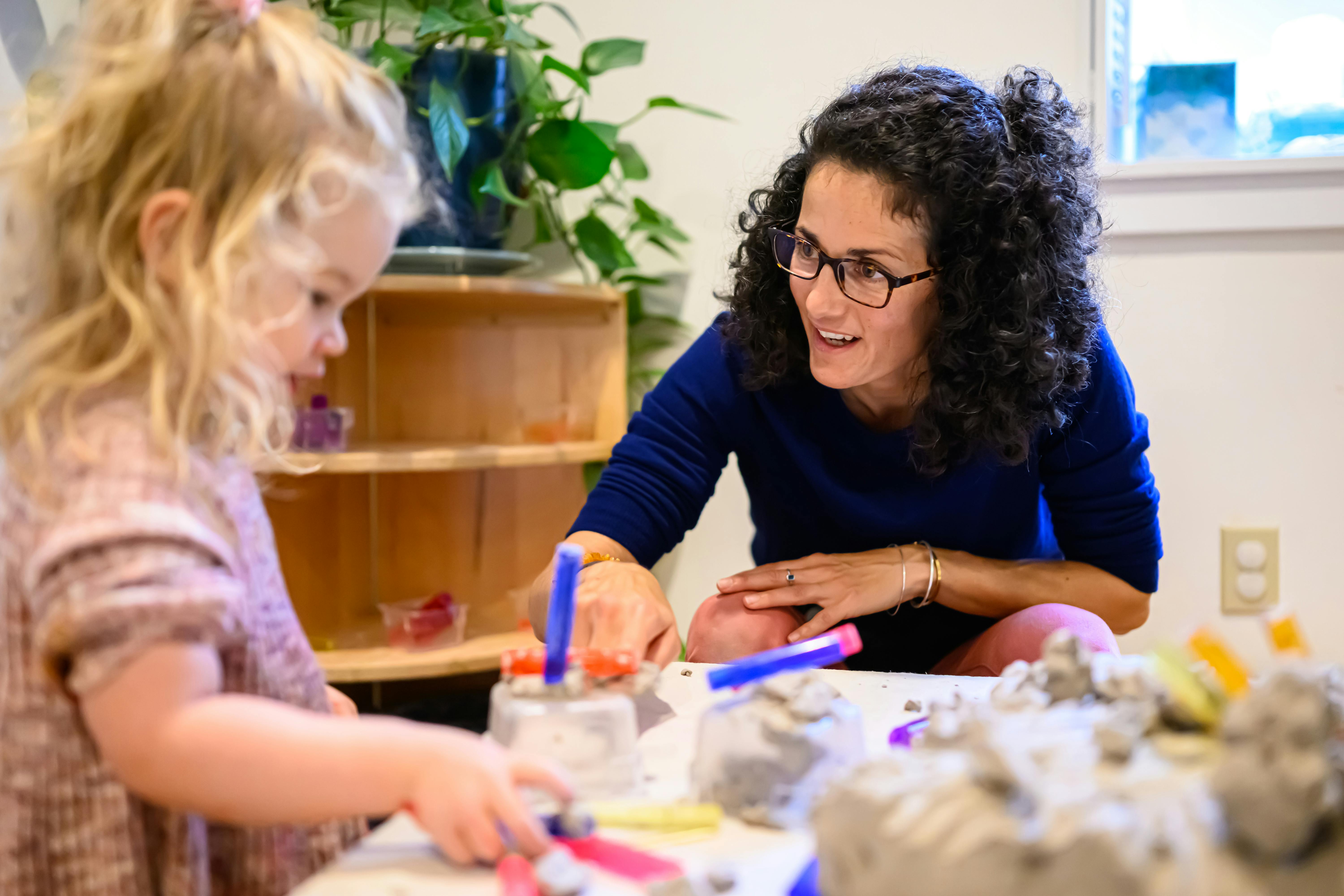 Adult and child playing with kinetic sand at a table