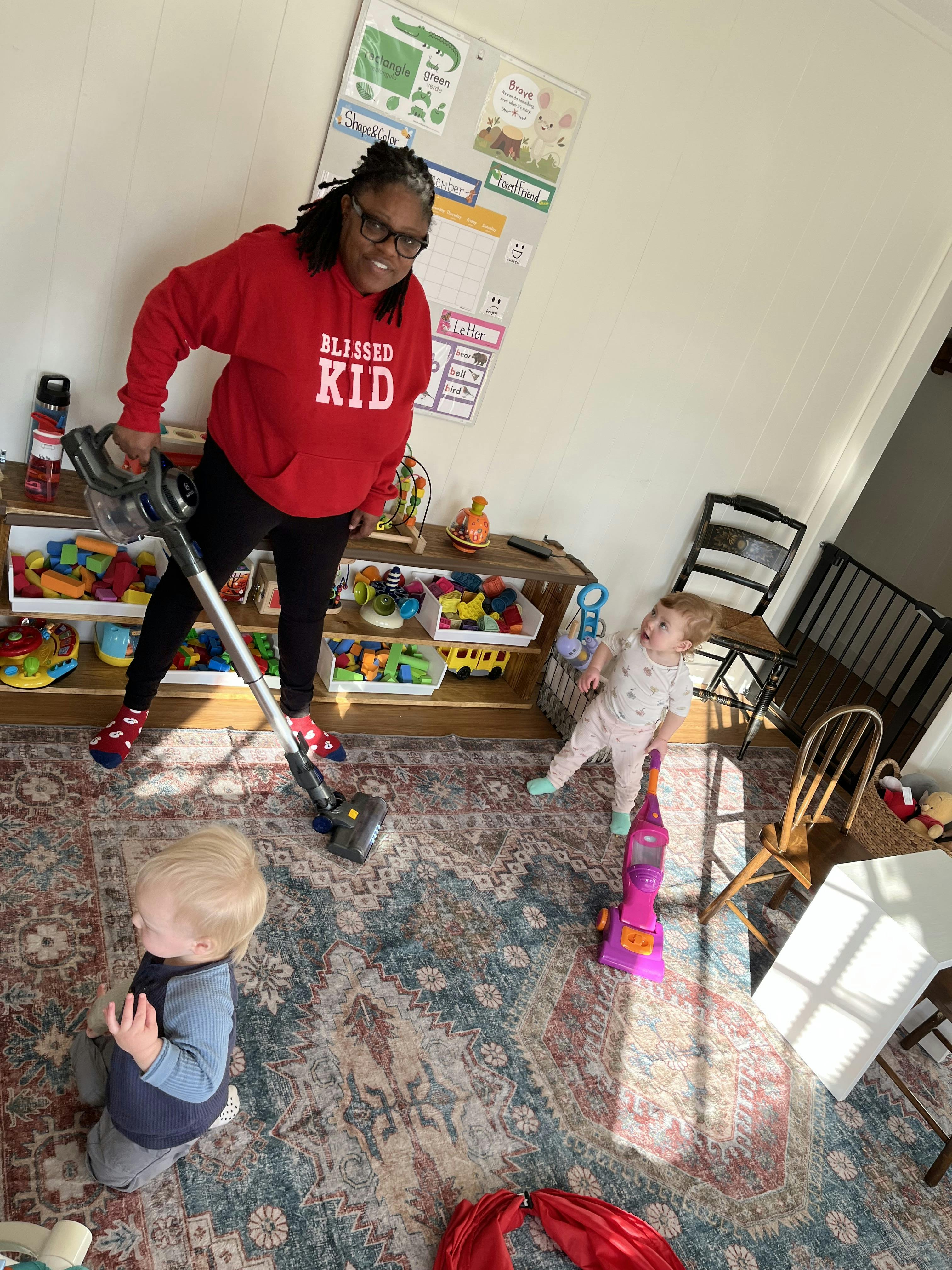 Person vacuuming with two children nearby
