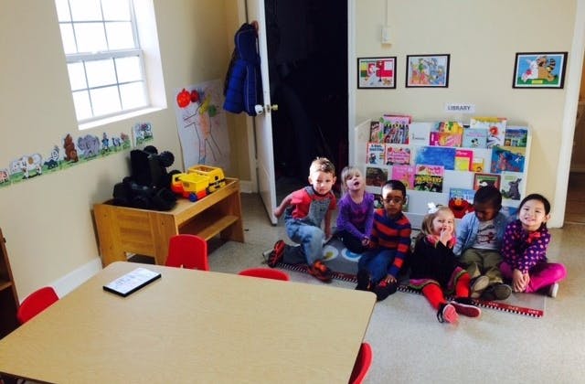 Six children sitting on the floor in a classroom