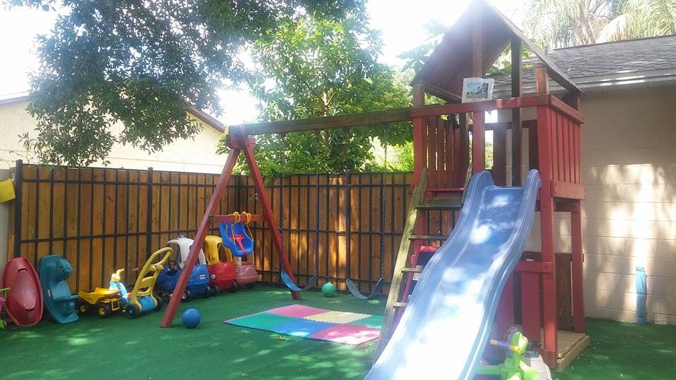 Playground with a slide, swings, and various toys on artificial turf
