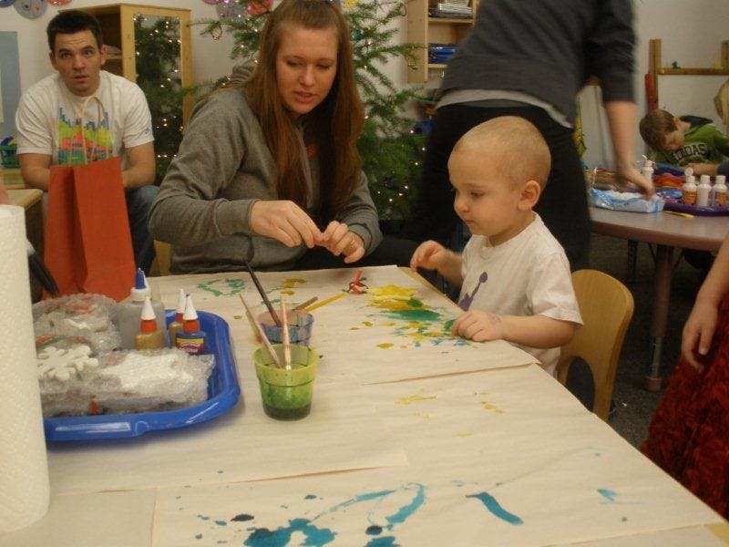 Person and child painting at a table
