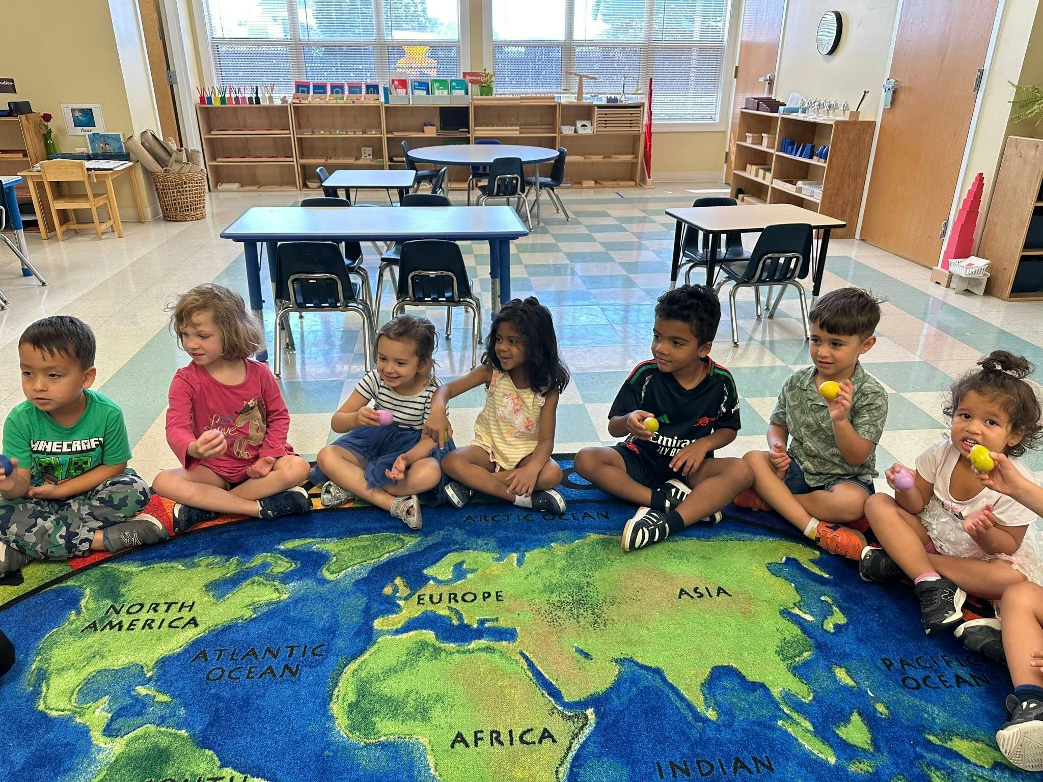 Children sitting on a world map rug in a classroom
