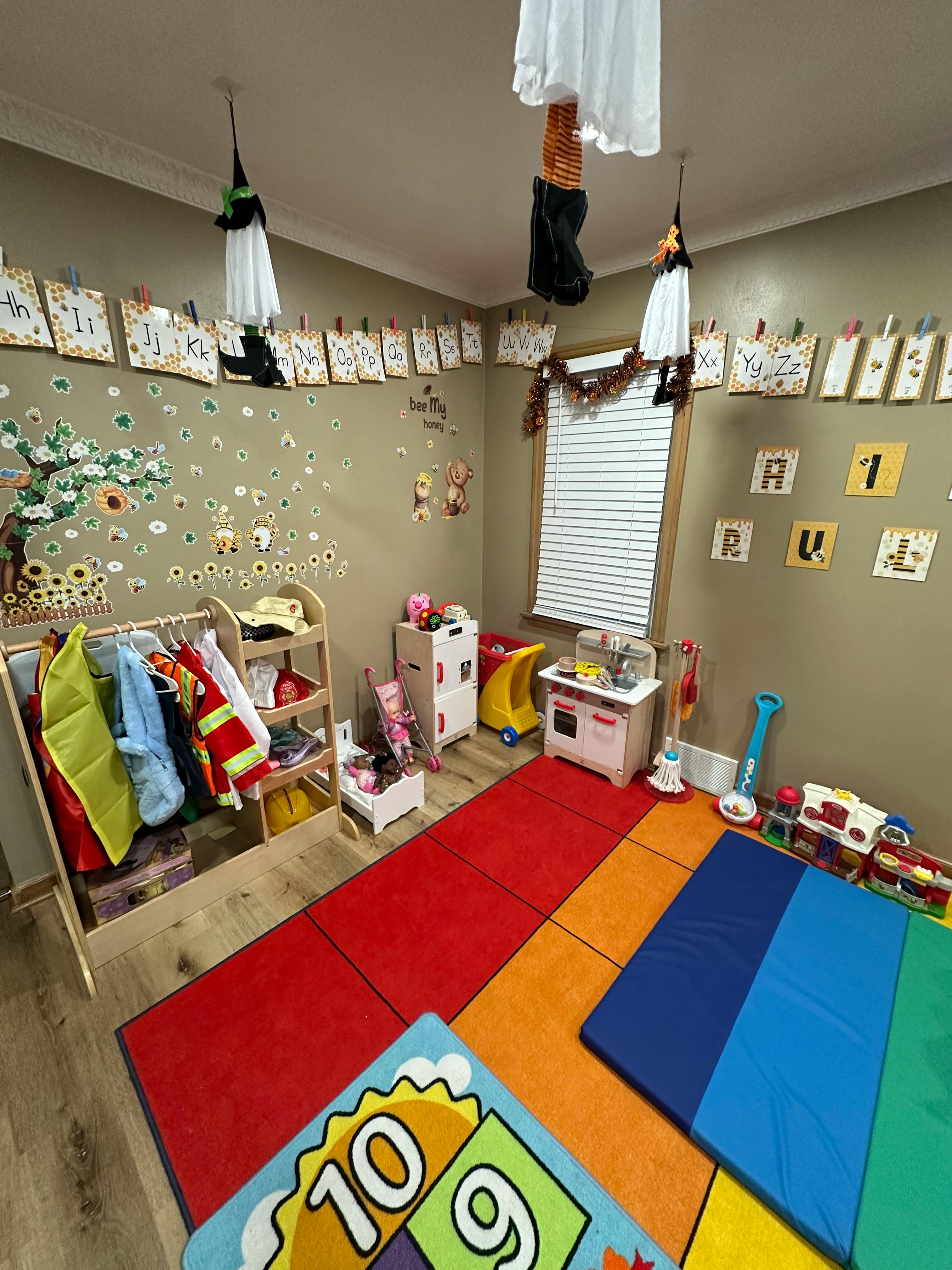 A classroom with colorful rugs, dress-up clothes, and play kitchen