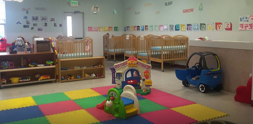 Daycare room with cribs, play mats, and toys