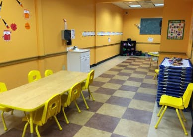 Empty classroom with yellow walls, long table, and chairs