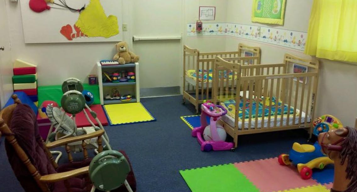 Nursery room with two cribs, play mats, and toys