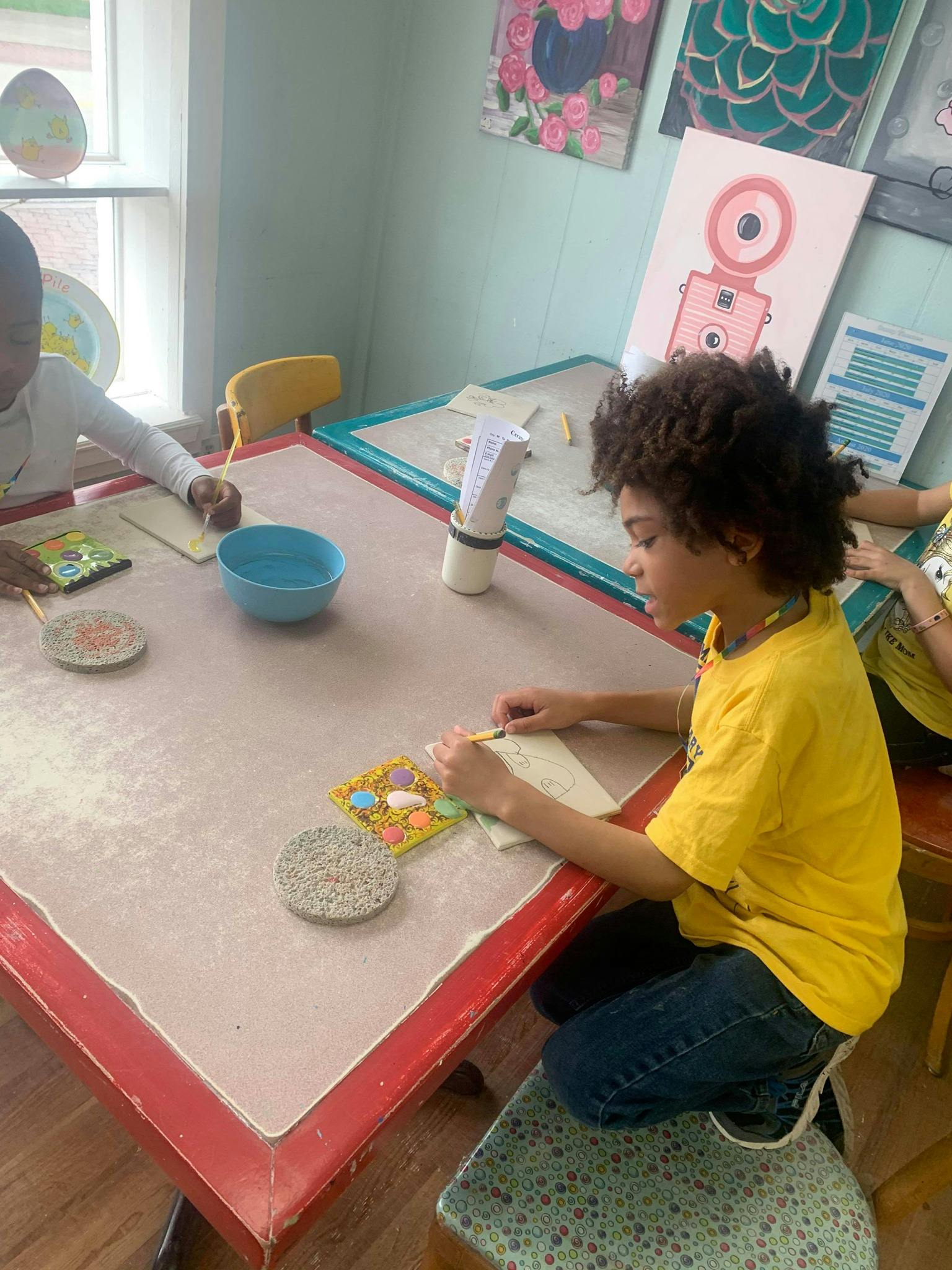 Child in yellow shirt working on a craft at a table