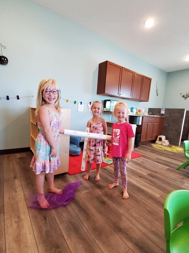 Three children holding a long white tube in a room