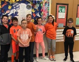 Seven children standing in a classroom