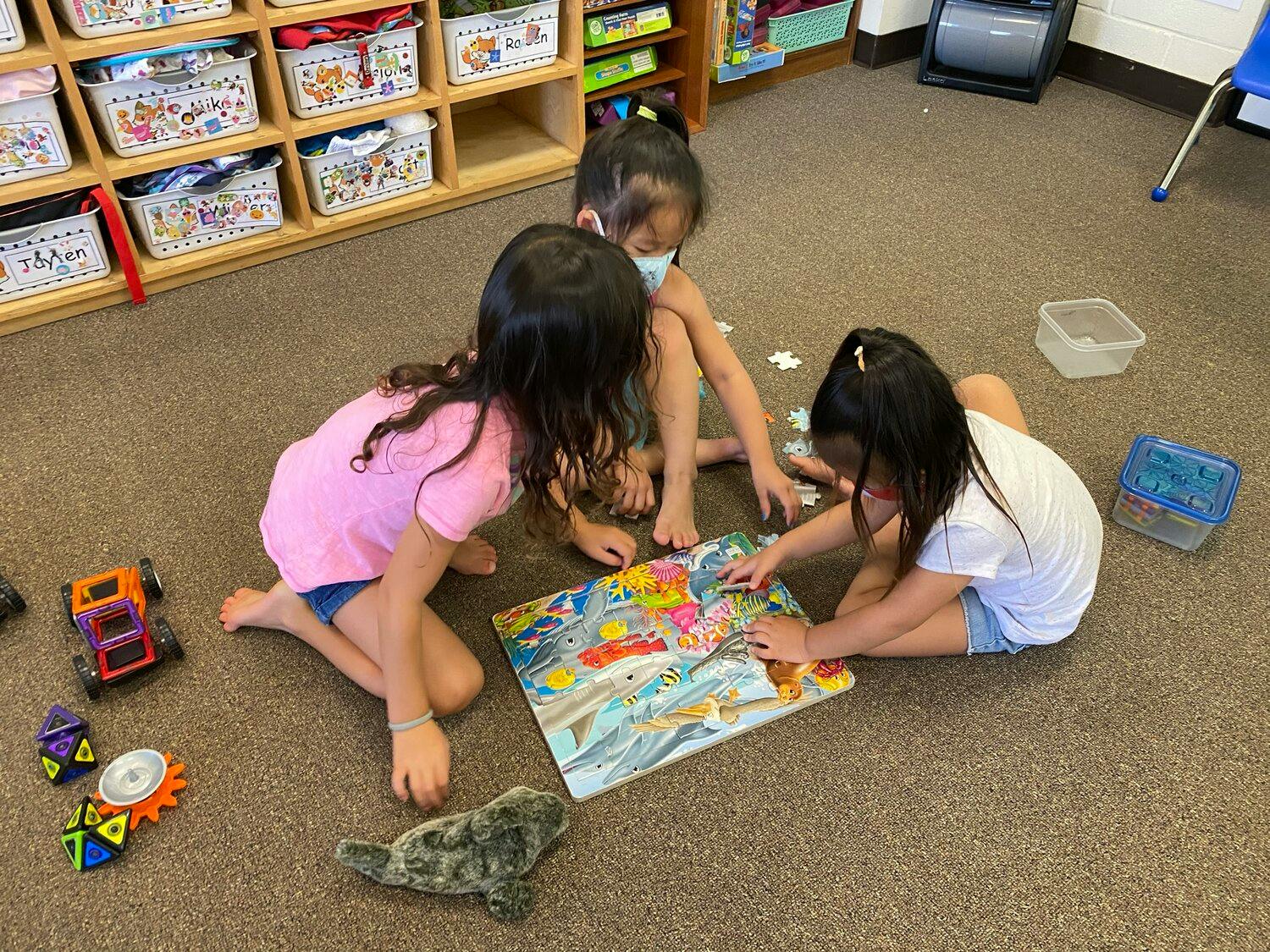 Three children on the floor assembling a puzzle