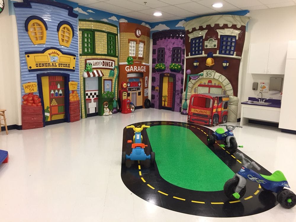Playroom with building facades and a road-themed mat with ride-on toys