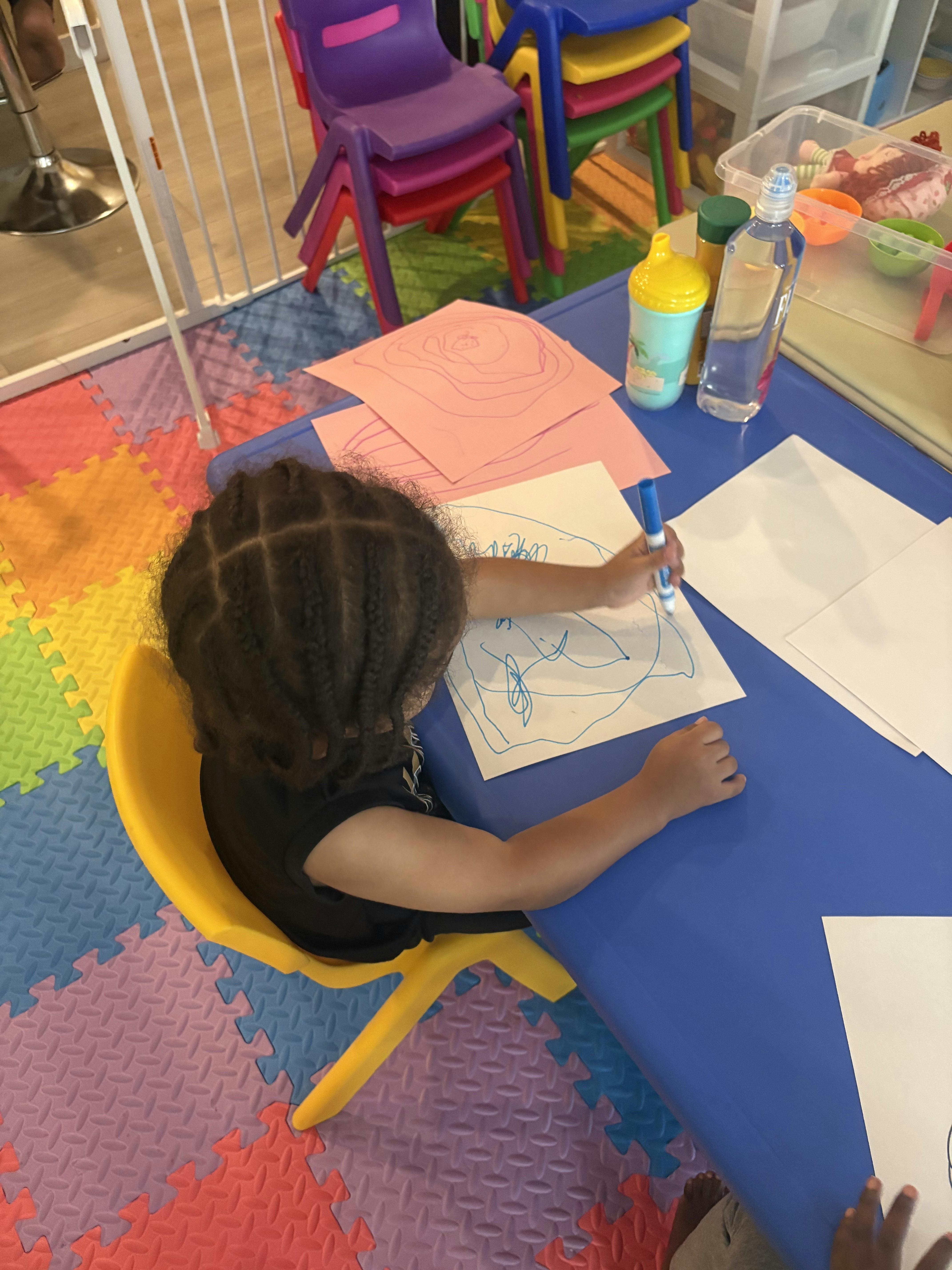 Child sitting at a table drawing with a marker