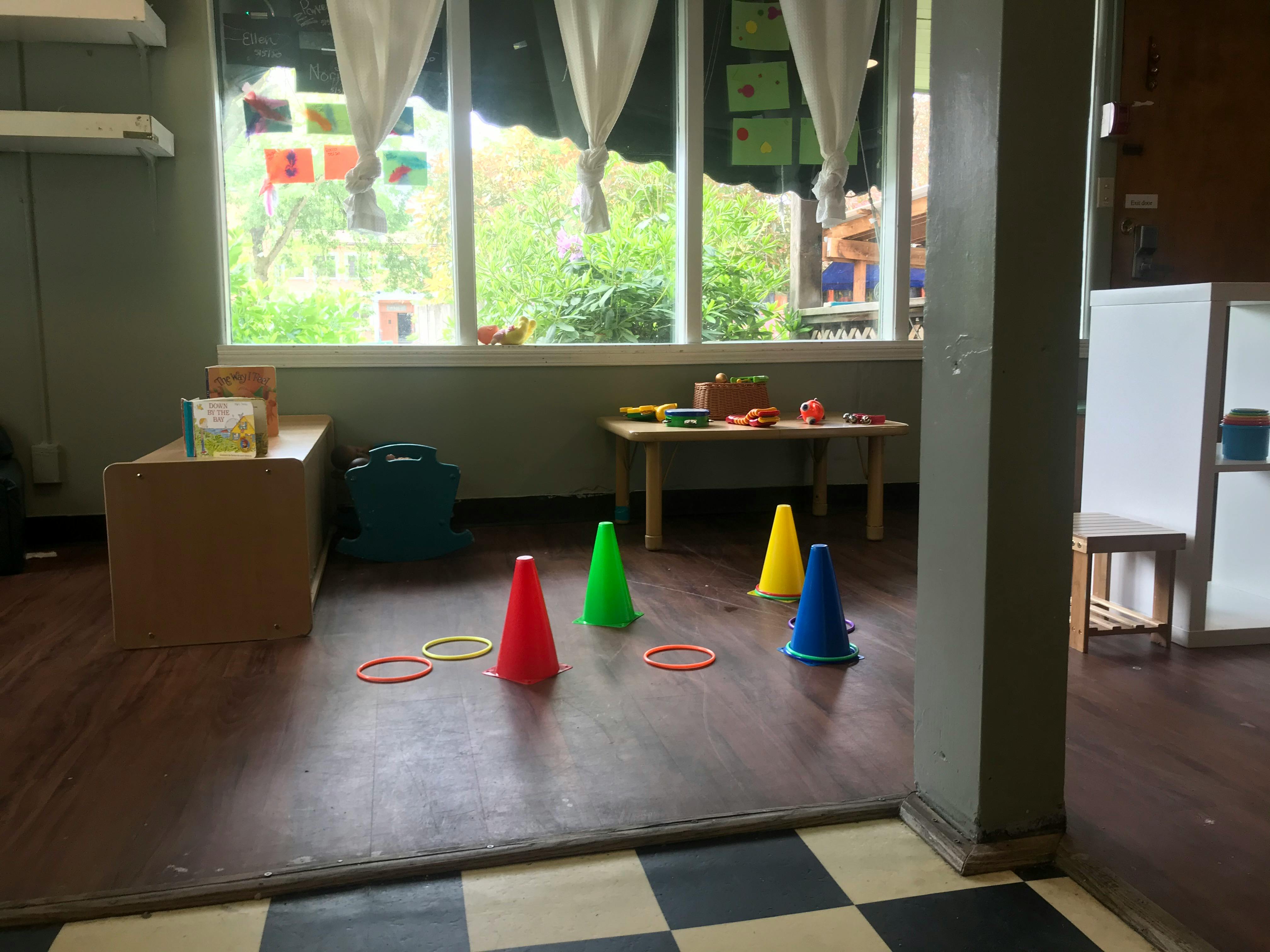 Colorful cones and rings on a wooden floor in a room with large windows