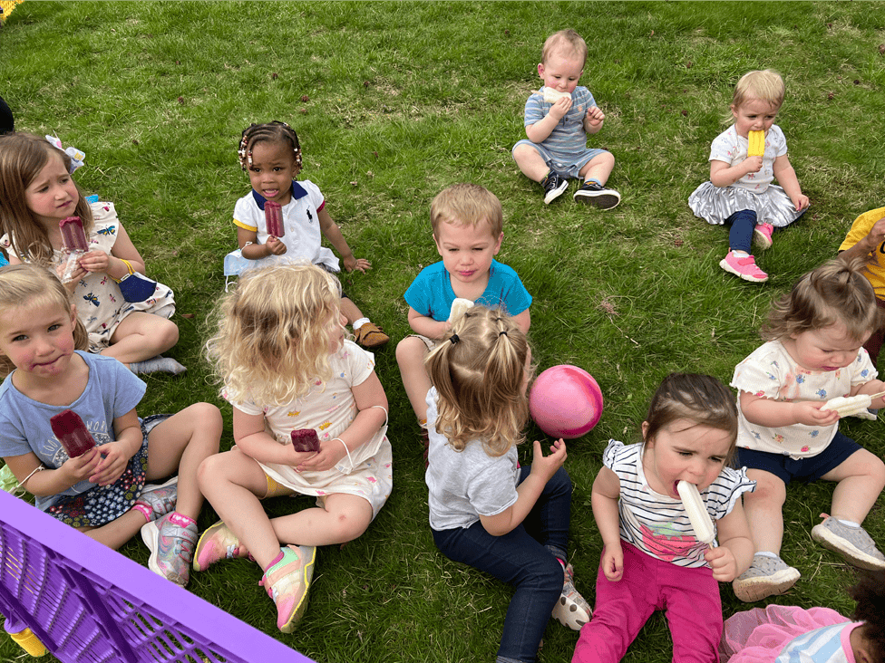Group of children sitting on grass eating popsicles