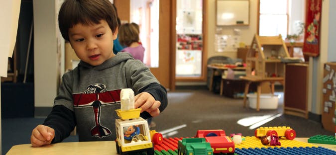 Child playing with toy truck and blocks in a classroom