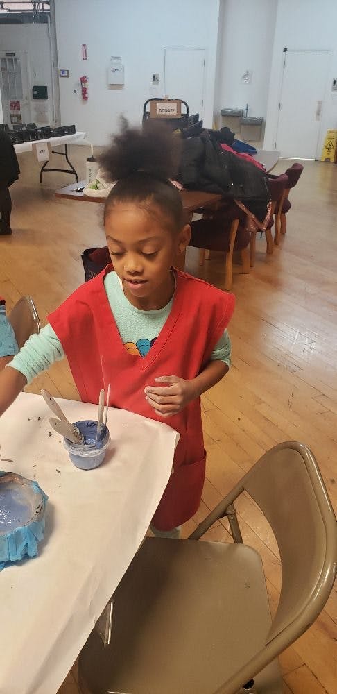 Child in a red smock painting at a table