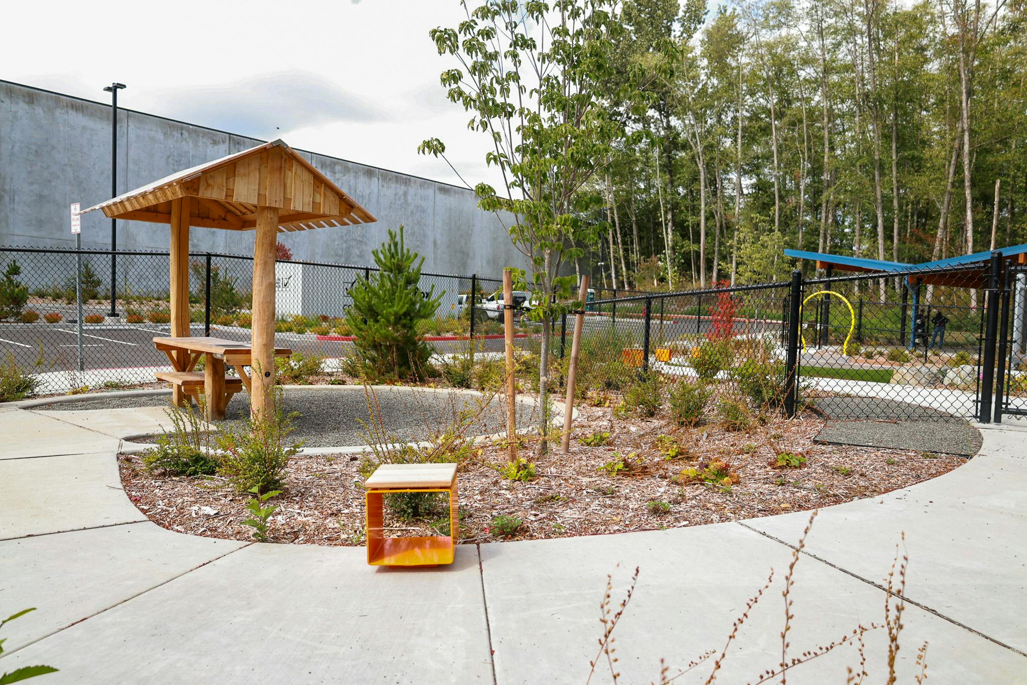 Wooden picnic shelter in a park with landscaping and a small orange seat