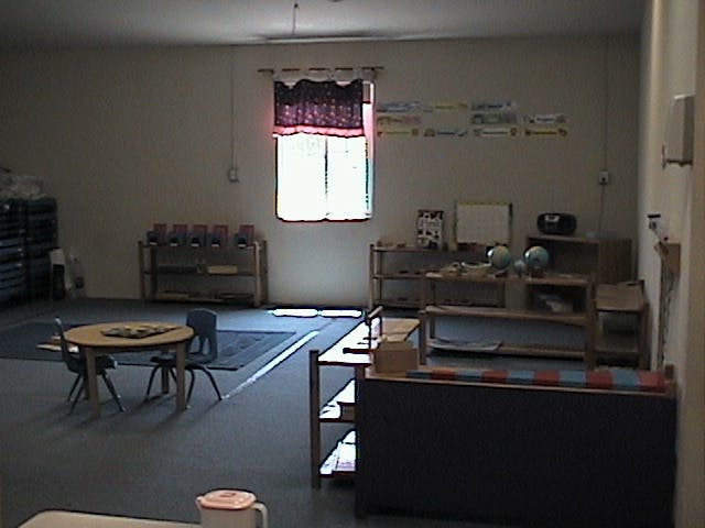 Classroom with small tables and shelves of learning materials
