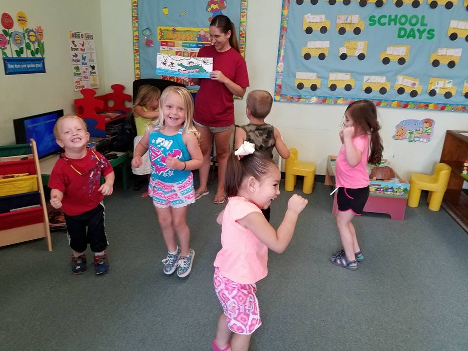 Adult holding a book for a group of children in a classroom
