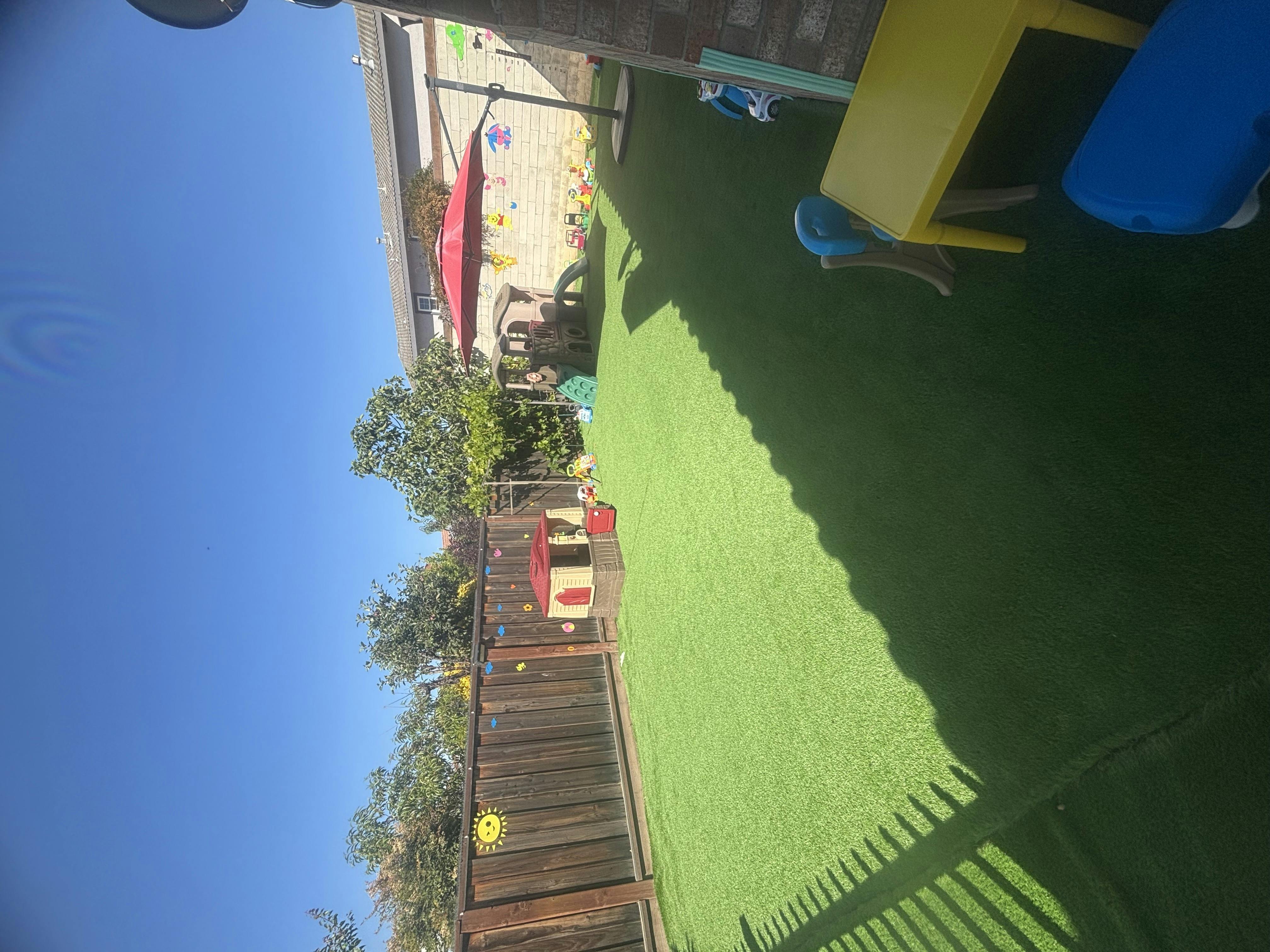 Backyard with artificial turf, playhouse, and patio furniture