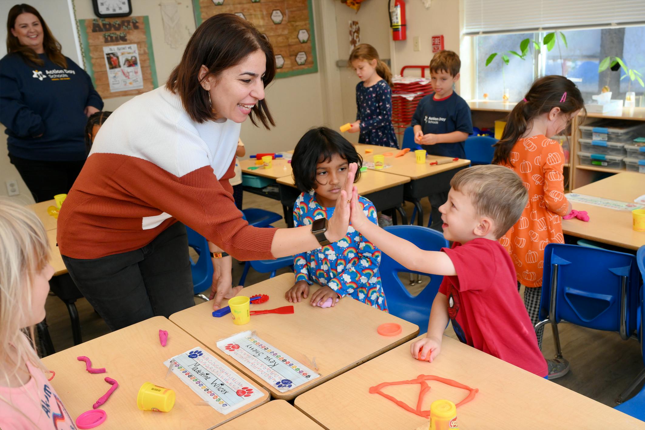 Adult giving a high five to a child in a classroom