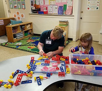 Adult and child playing with building blocks at a table