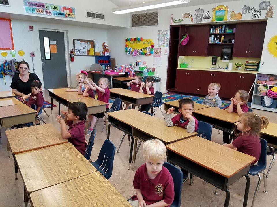 Adult and children sitting at desks in a classroom