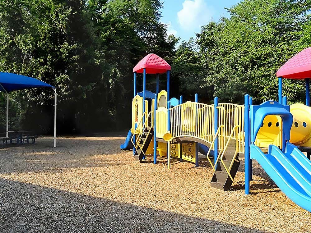 Playground with blue and yellow play structure, slides, and blue canopy