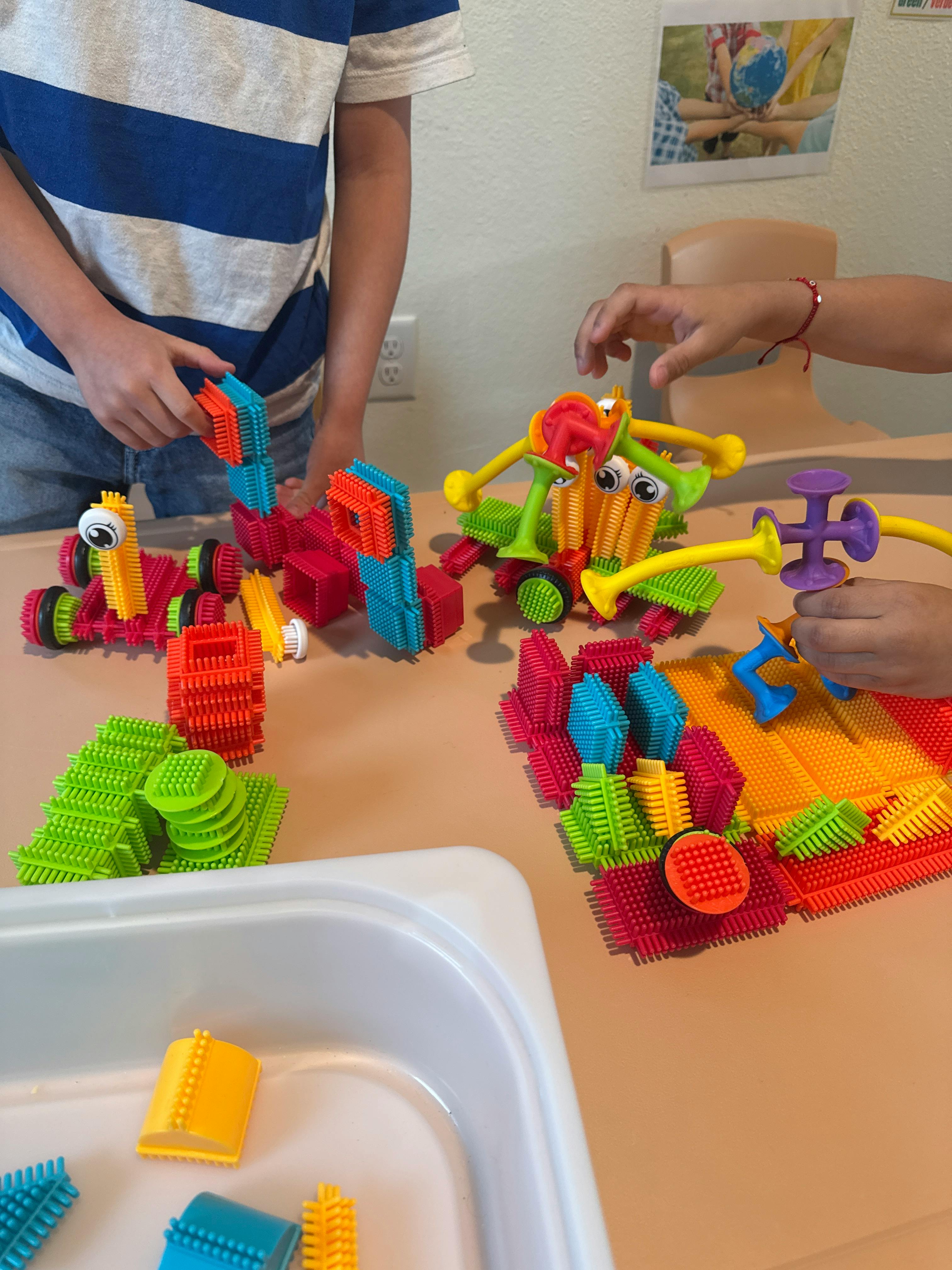 Two children playing with colorful building toys on a table