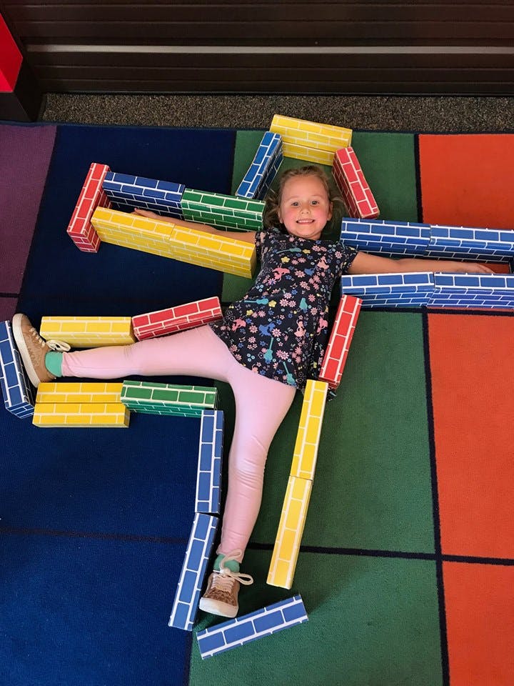 Child lying on floor surrounded by colorful block toys
