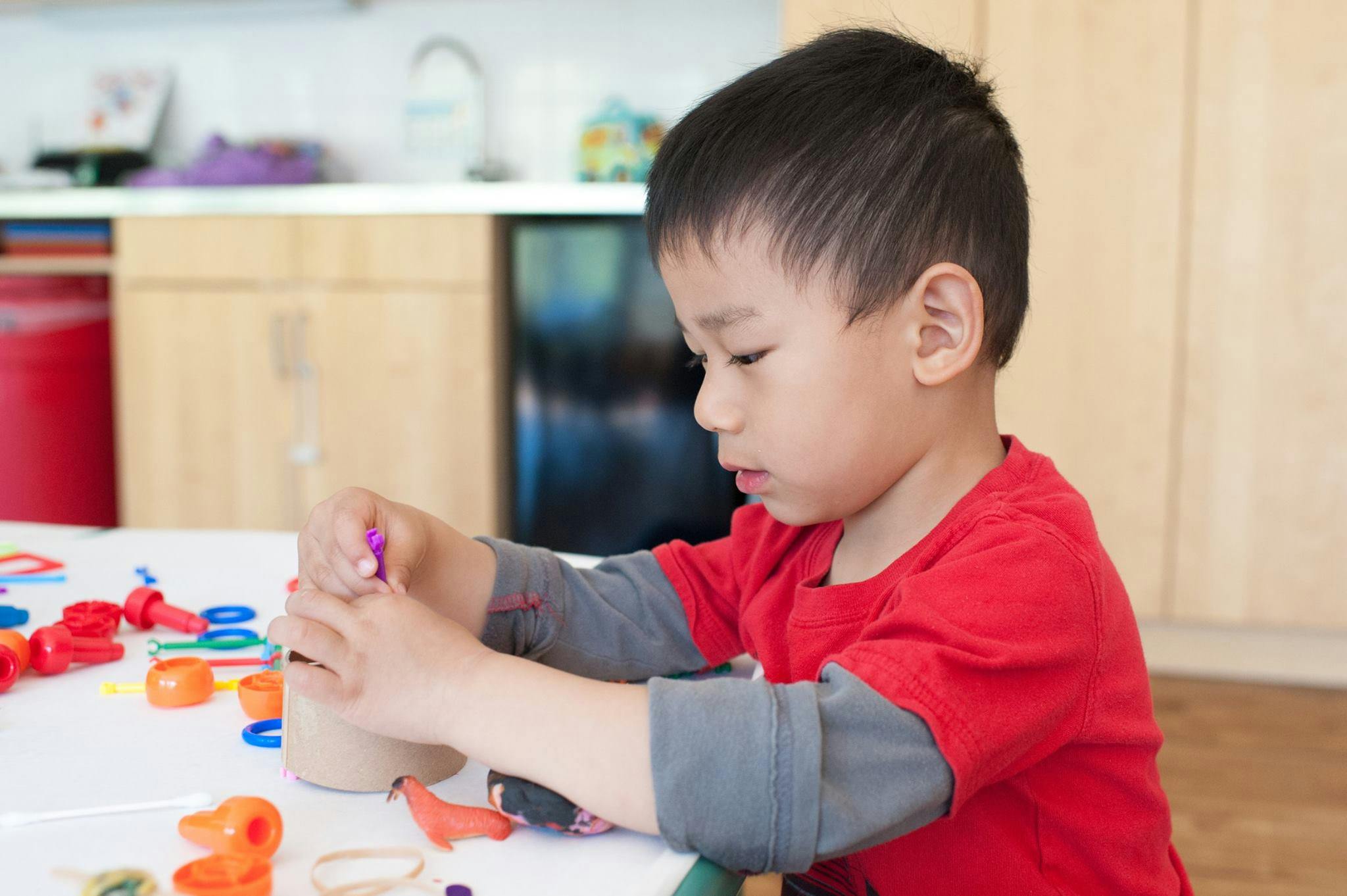 Child playing with craft supplies at a table