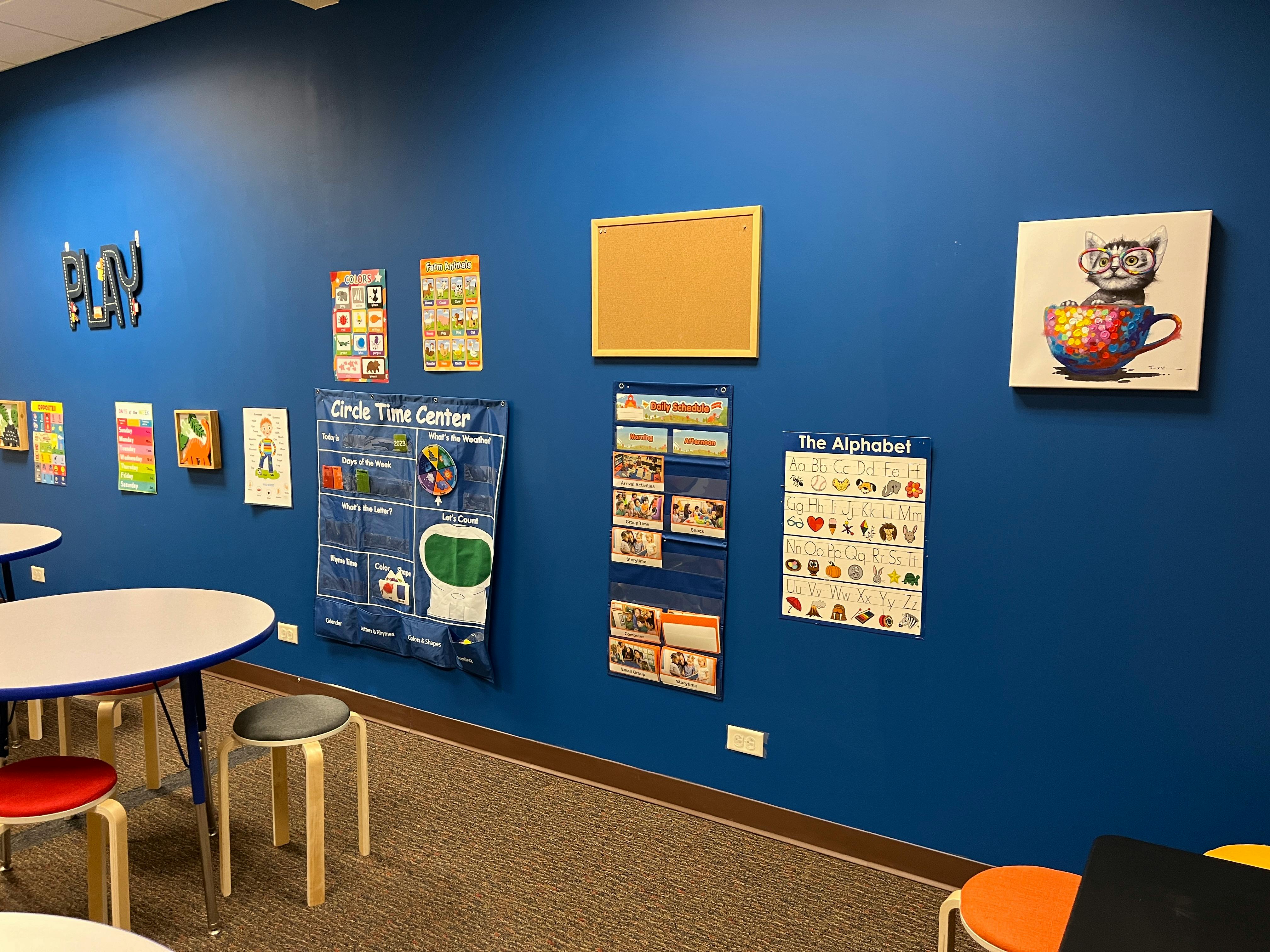 Classroom wall with educational posters and tables with tables and stools in the foreground
