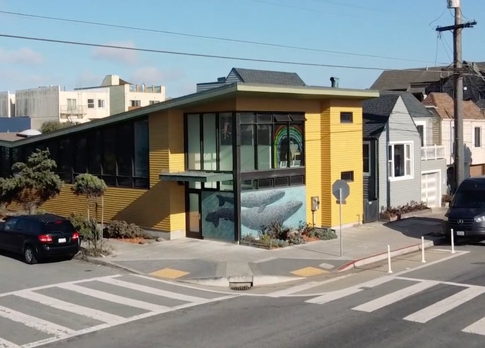 Yellow building with large windows and a whale mural on the side