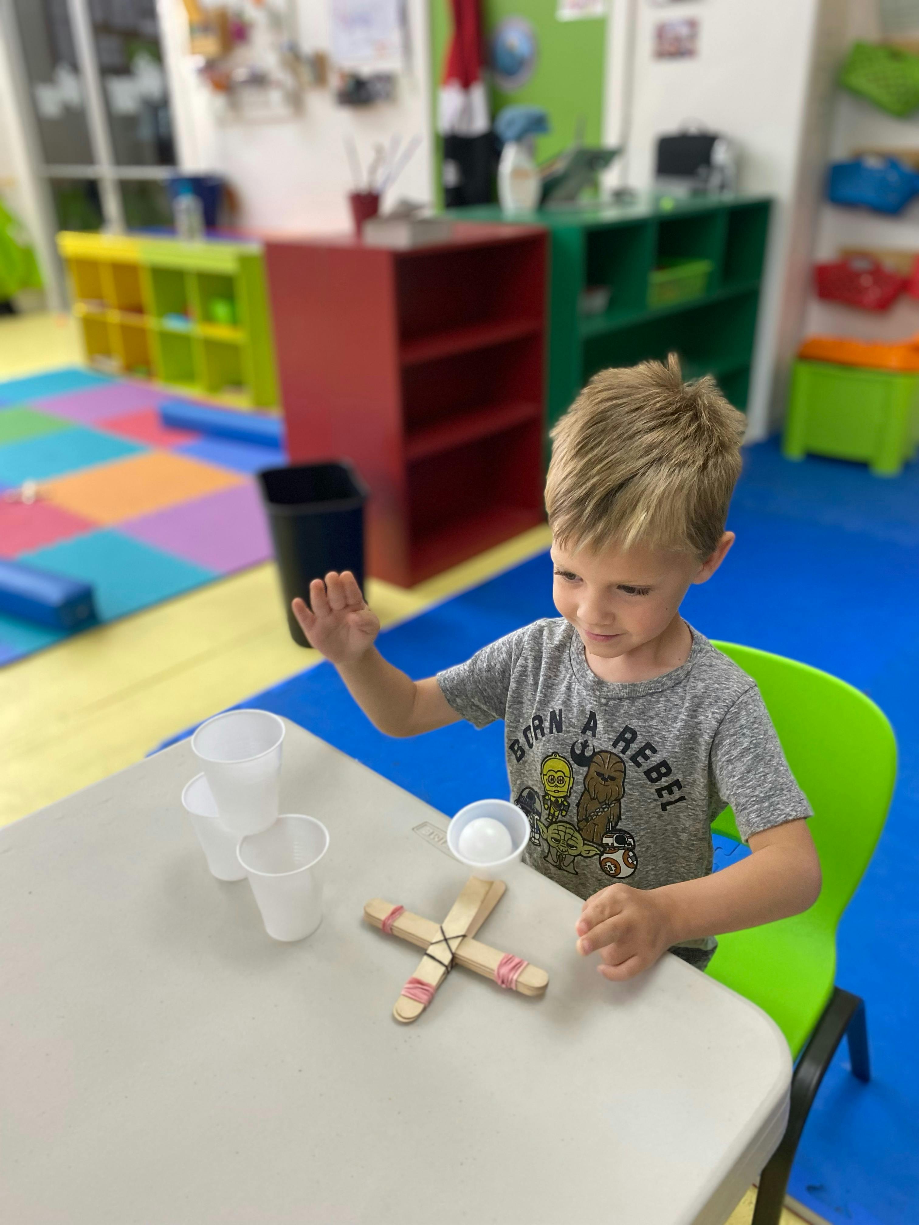 Child at a table with craft sticks and plastic cups