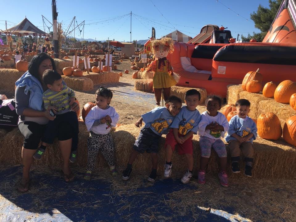 Adult and children sitting on hay bales at a pumpkin patch