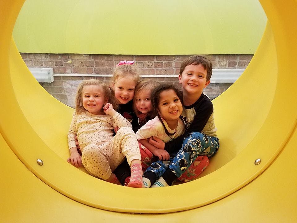 Group of children sitting inside a yellow playground slide