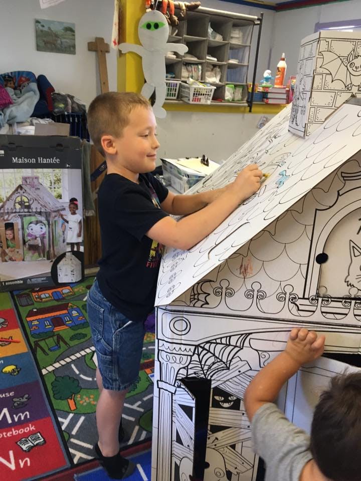 Child coloring a cardboard playhouse