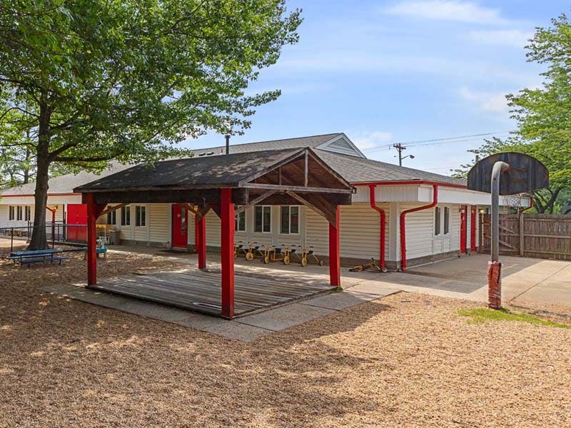 Outdoor school playground with a wooden shelter, building, and basketball hoop