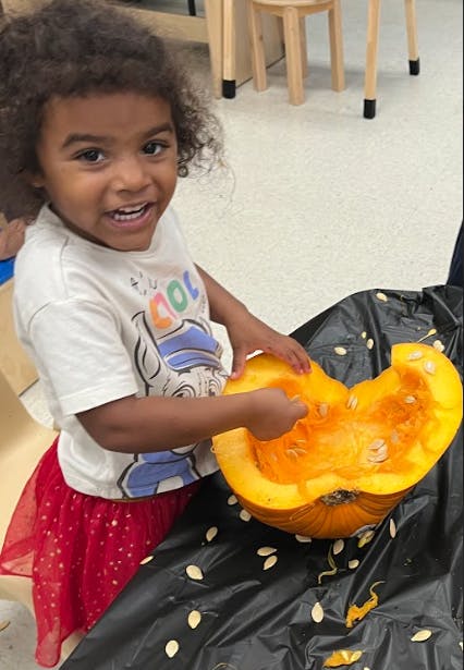 Child scooping seeds from a pumpkin