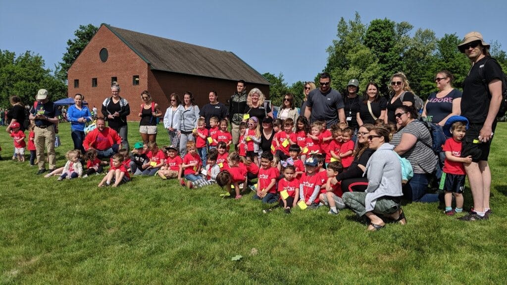 Group of adults and children in red shirts posing on grass