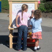 Two children writing on an easel