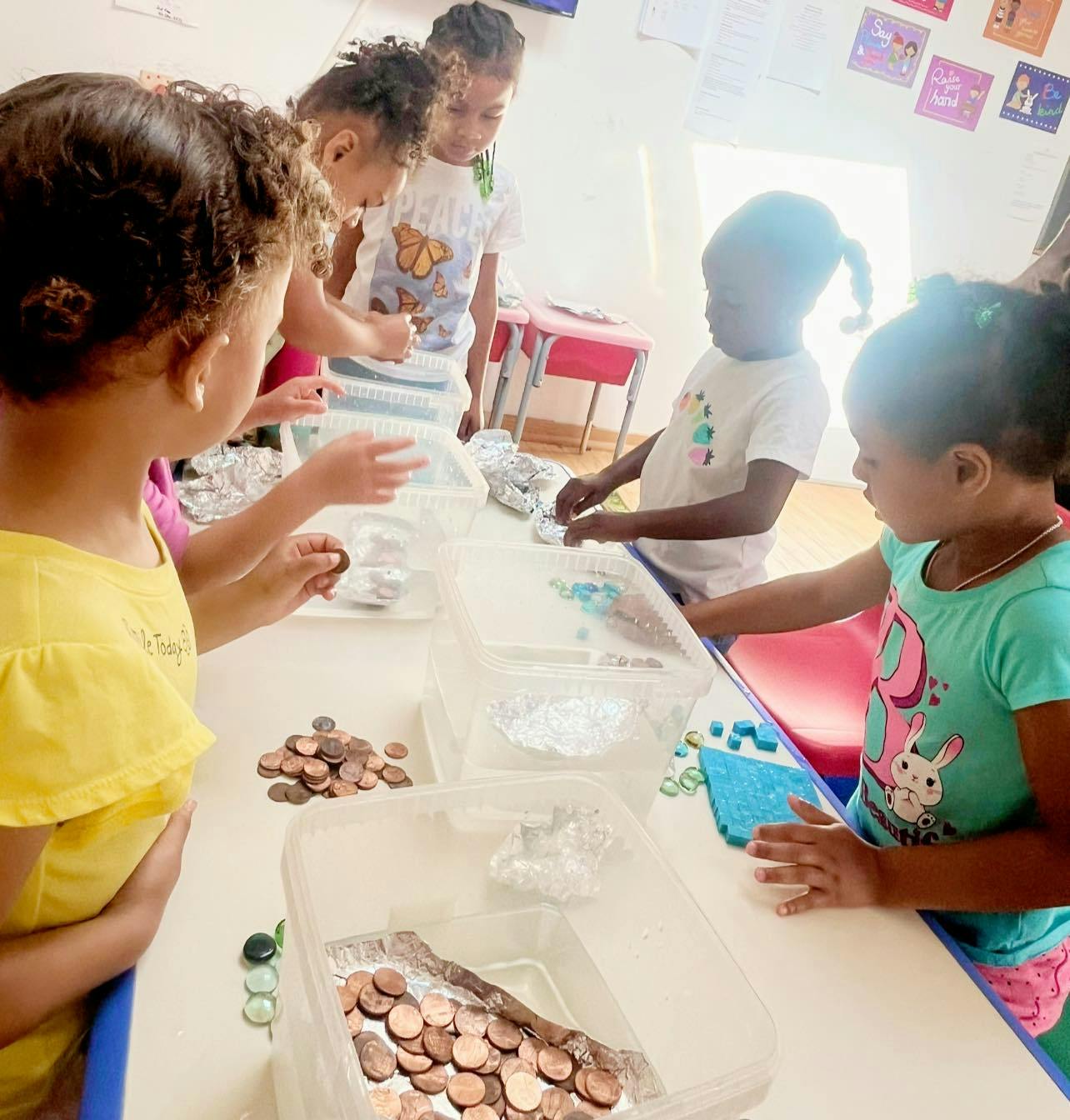 Children sorting coins and small objects into clear containers