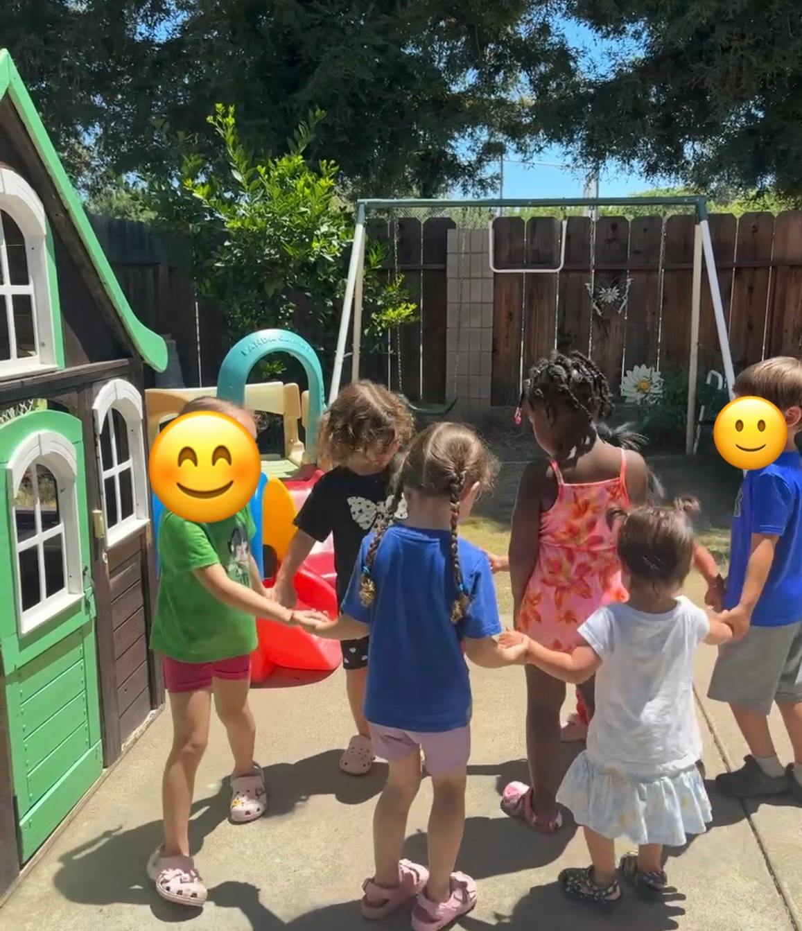 Group of children holding hands in a circle in a backyard