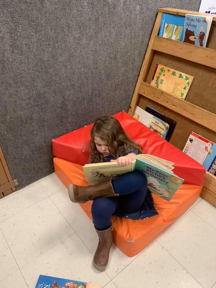 Child sitting on a beanbag chair reading a book