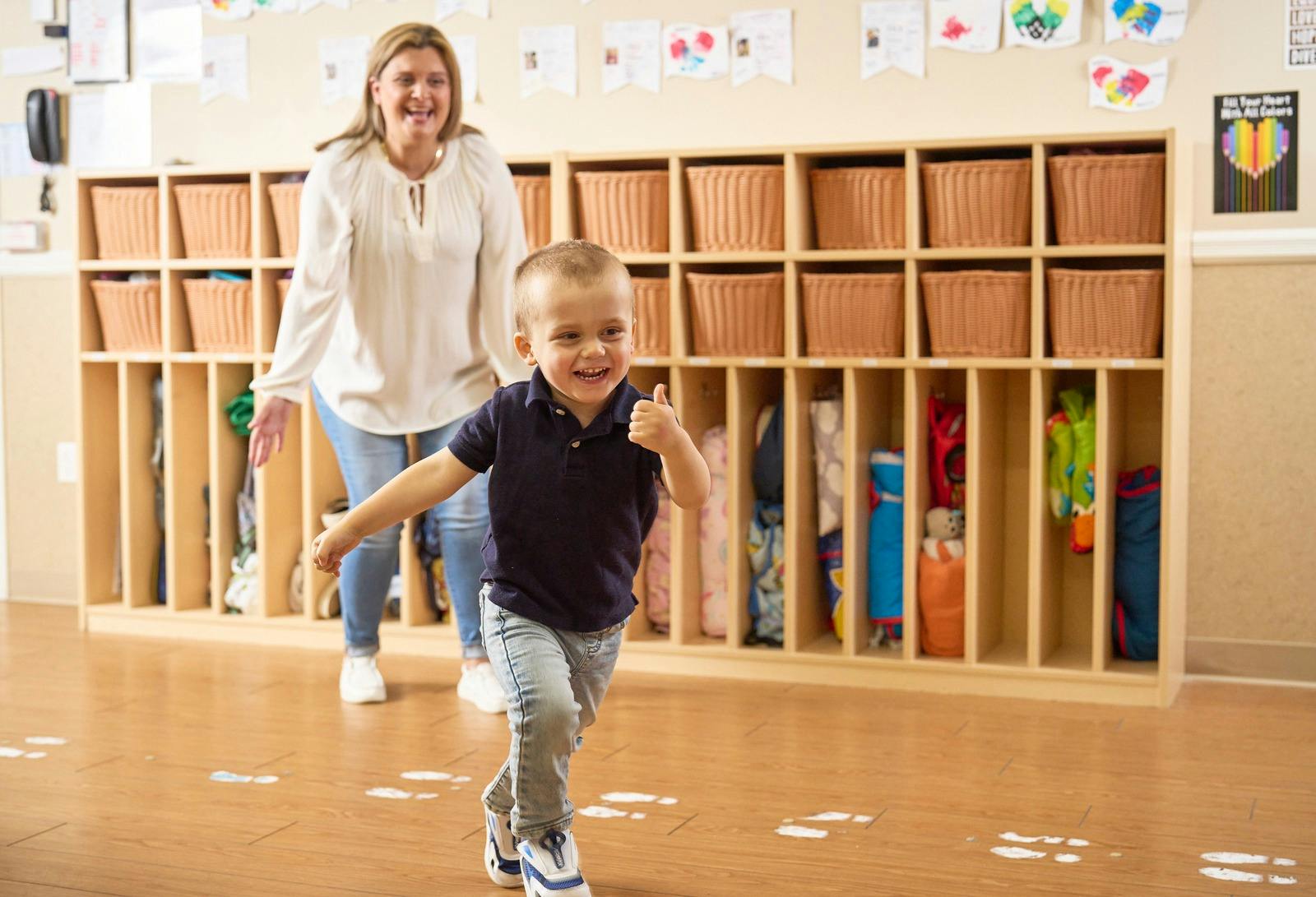 Adult and child running in a classroom