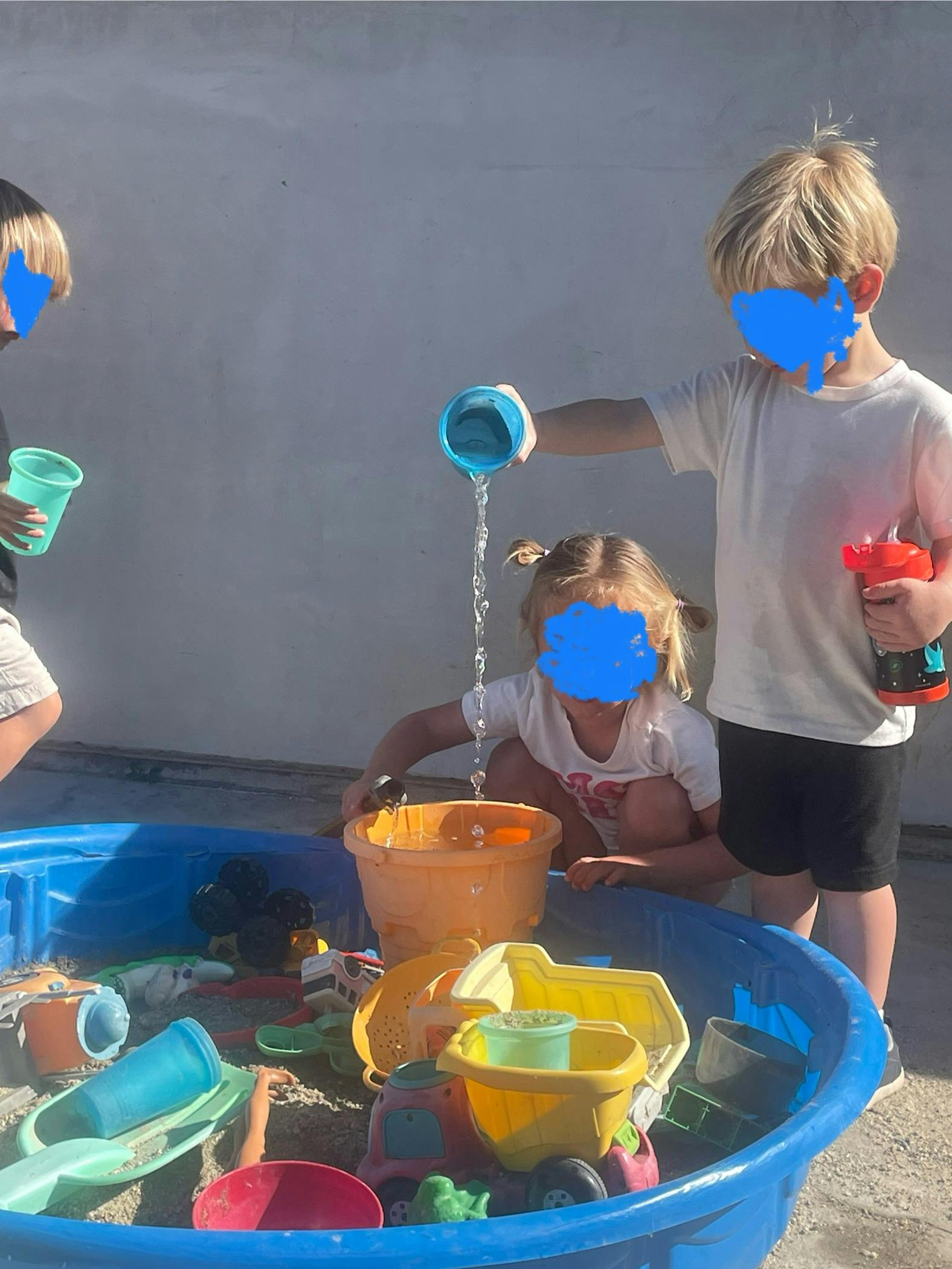 Children playing with water and toys in a plastic pool